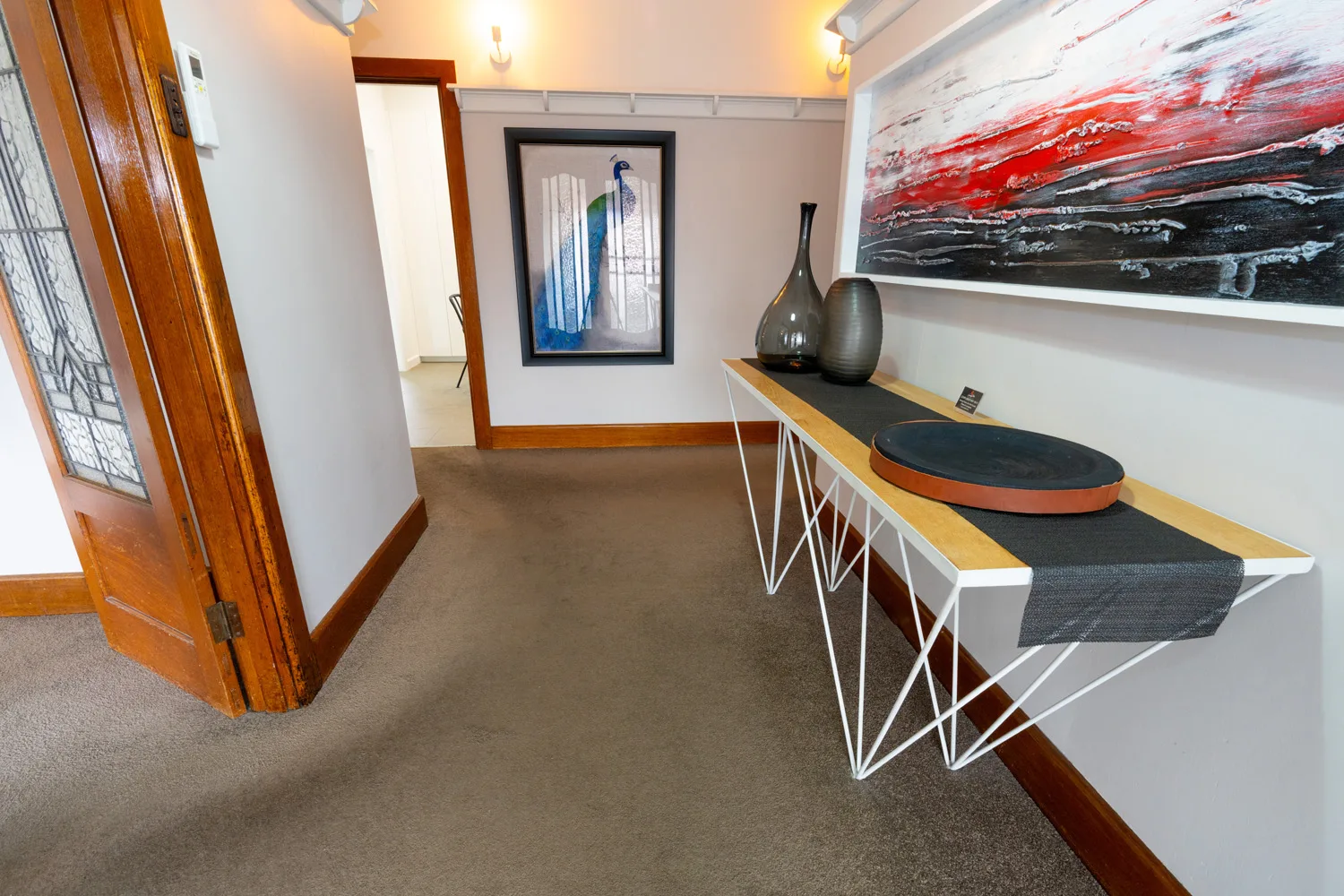 A carpeted entry hall connects timber-framed doorways, with a console table along the right wall.