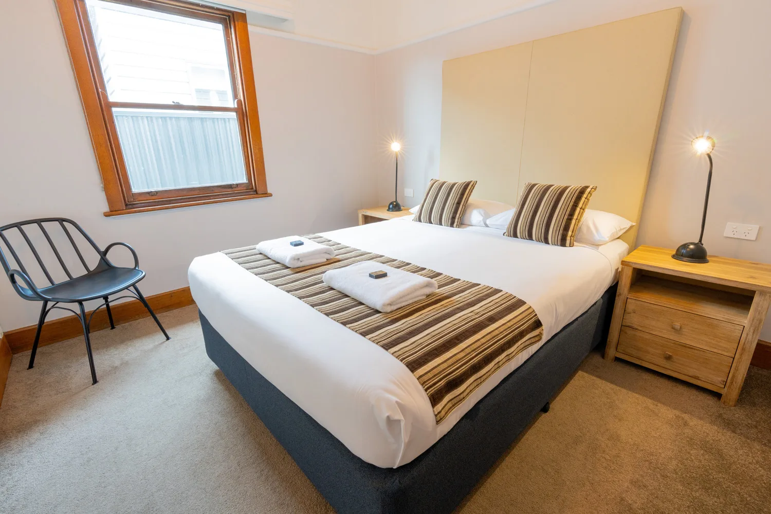 A neatly made bed in the bright Eureka bedroom at Sovereign Park Motor Inn.