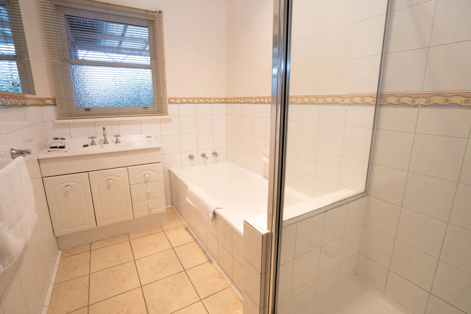 Bathroom with a vanity, bathtub and glass-enclosed shower.