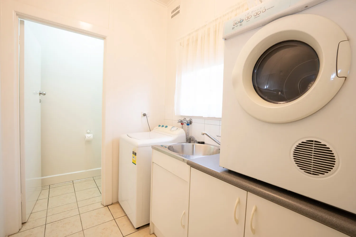 Laundry room with a front-loading dryer, washing machine and sink.
