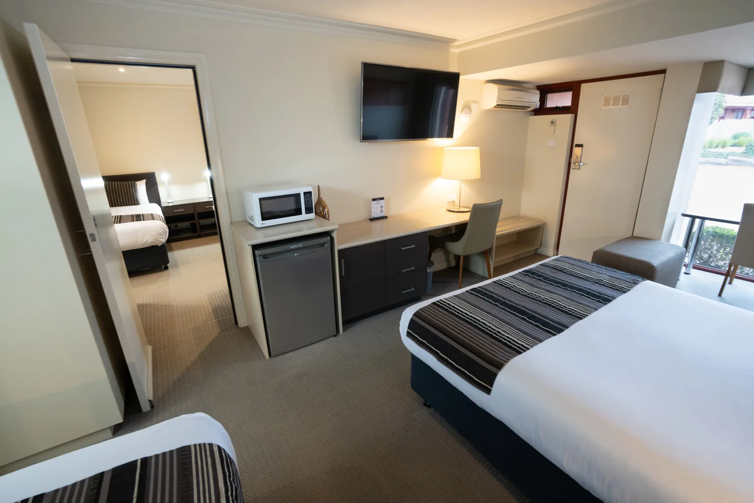 A guest room at Sovereign Park Motor Inn with beds, a desk and a microwave.