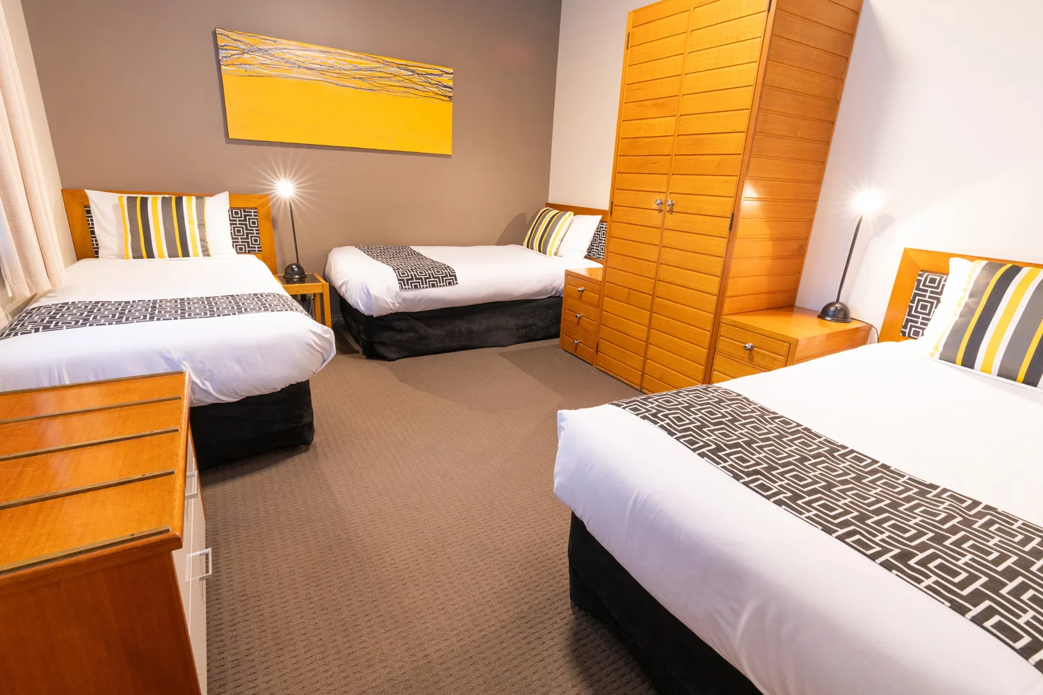 Three single beds are arranged in the second bedroom of a two-bedroom unit.