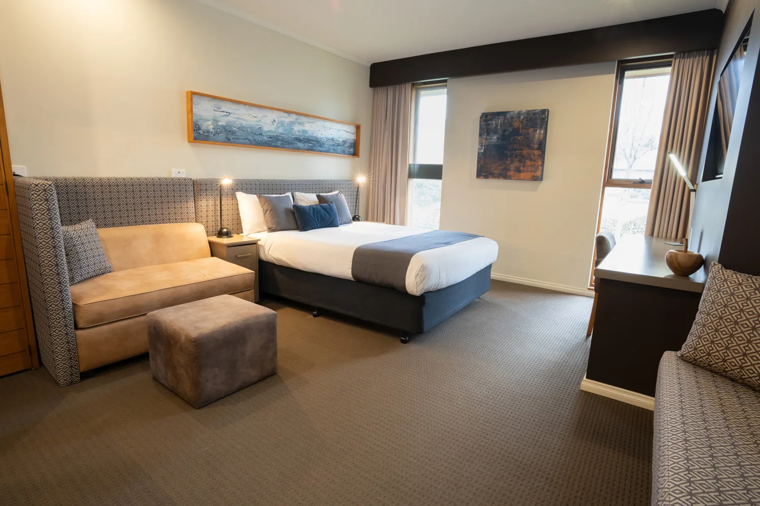 Queen bed, sofa and contemporary furnishings in a naturally lit room at Sovereign Park Motor Inn.