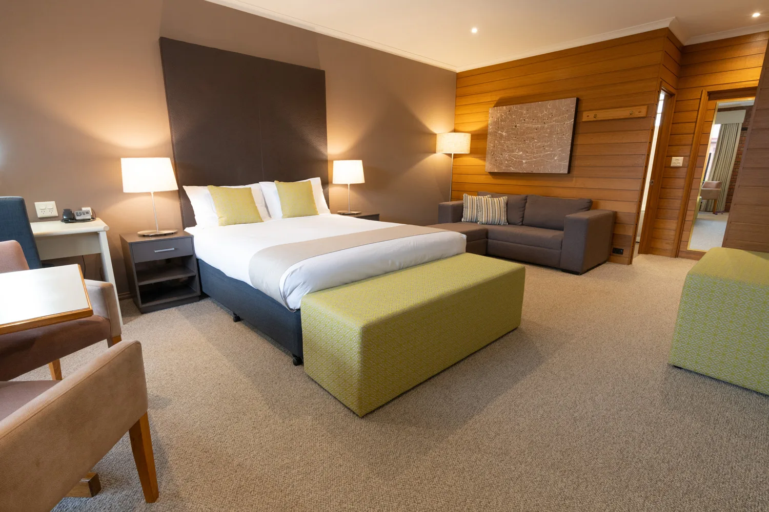 Queen bed and lounge seating in a warmly lit bedroom at Sovereign Park Motor Inn.