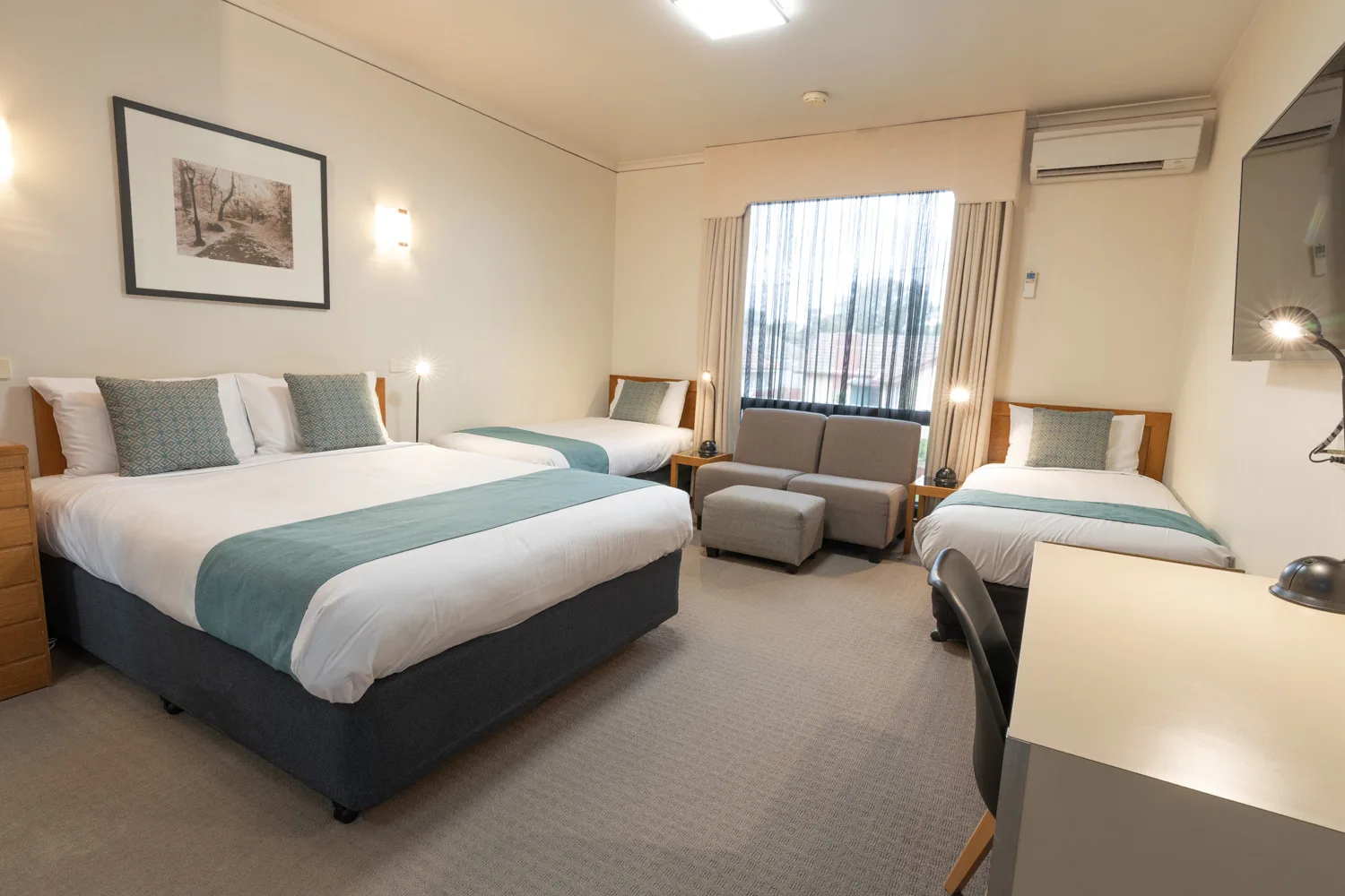 A family room at Sovereign Park Motor Inn in Ballarat with three beds and a seating area.