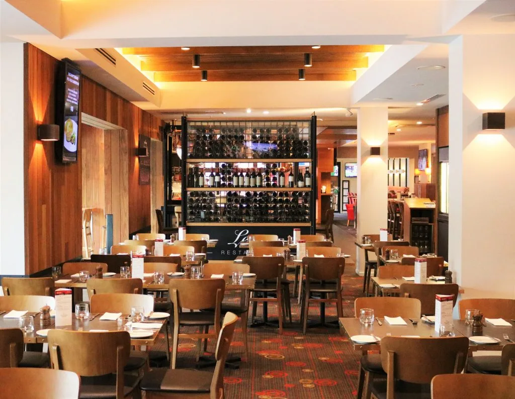 Set tables and a central wine display fill the dining room, with a sign reading Leo's Restaurant.