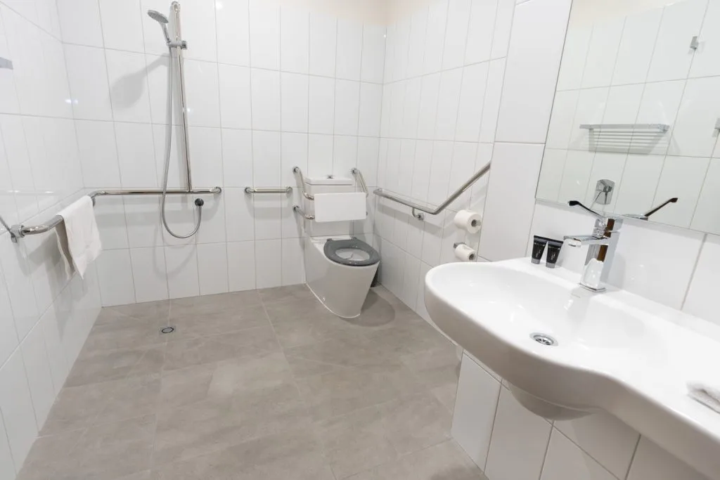 Accessible bathroom at Sovereign Park Motor Inn with an open shower, grab rails and handheld shower head.